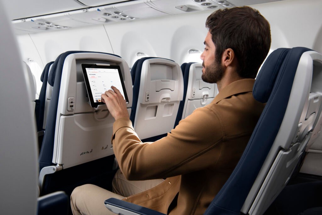 Voyageur consultant sa tablette à bord d'un Airbus A220 d'Air France